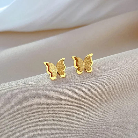Aretes en forma de mariposa con tonos cafés y dorados